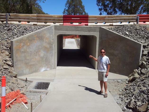 Man standing on concrete ramp leading to tunnel under a road